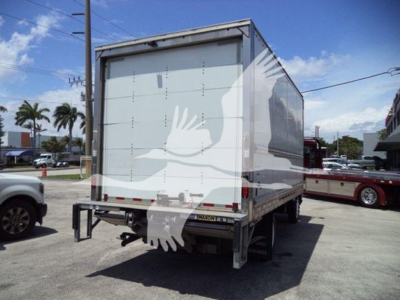 Box truck rear view with closed cargo area and bumper step; Isuzu NPR flatbed or box truck silhouette visible in lot.