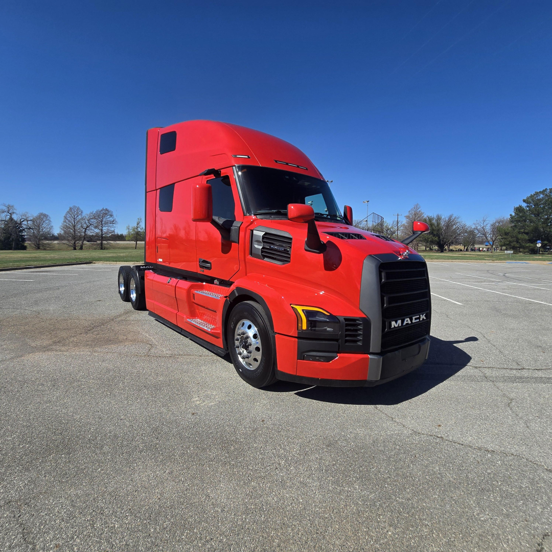 Red 2026 Mack PR64T76H conventional sleeper truck side/front view showing large grille and Mack emblem.