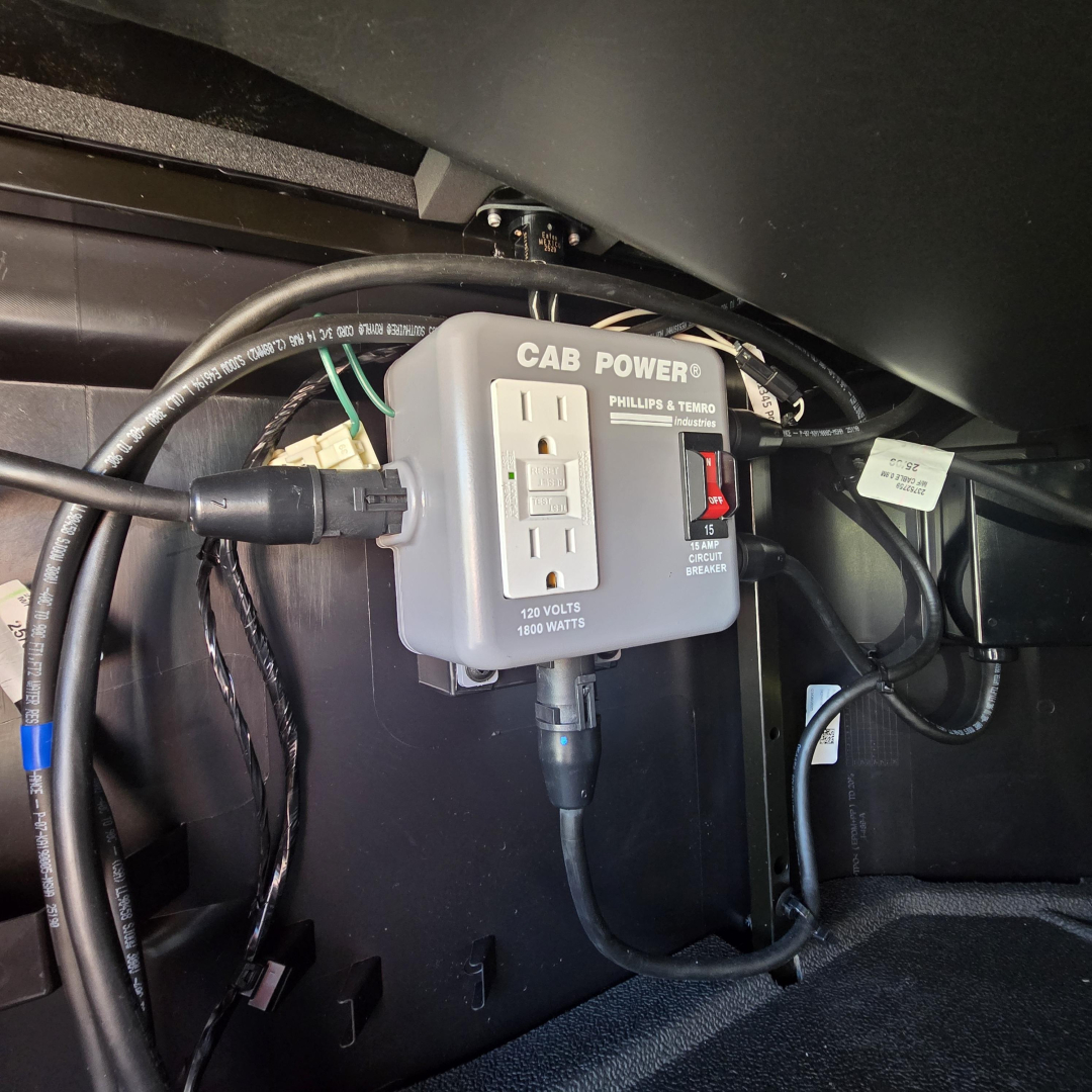 Cab Power electrical outlet device mounted under dashboard with two-prong outlet and switch labeled CAB POWER PHILLIPS TEMRO, in-service wiring harnesses visible.
