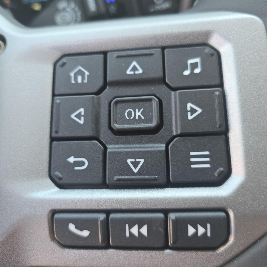 Truck cockpit control pad with OK button and navigation arrows visible.