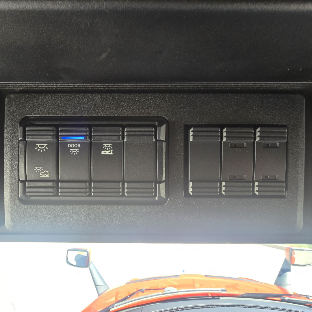 Dashboard switches and control panel in Mack PR64T76H cab showing multiple rocker switches with symbols for lights and door/parking functions.