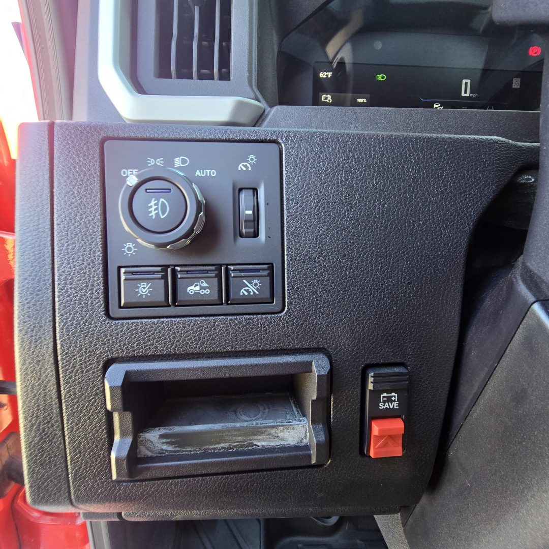 Mack PR64T76H interior left dashboard controls with headlight dial, several switches, and storage slot.