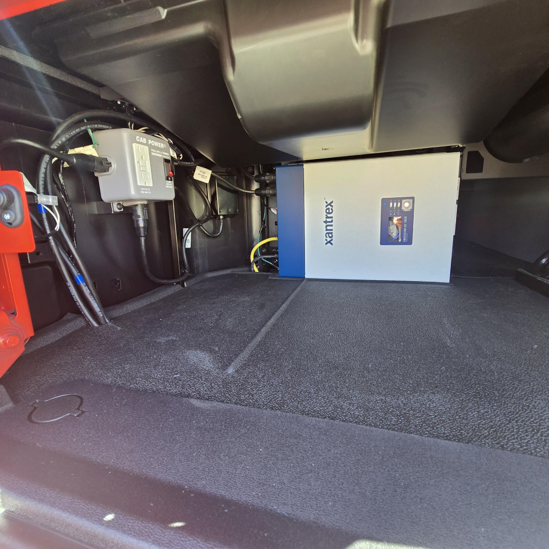Mack PR64T76H truck cab area showing Xantrex inverter box mounted in cargo bay with wiring and control module nearby.