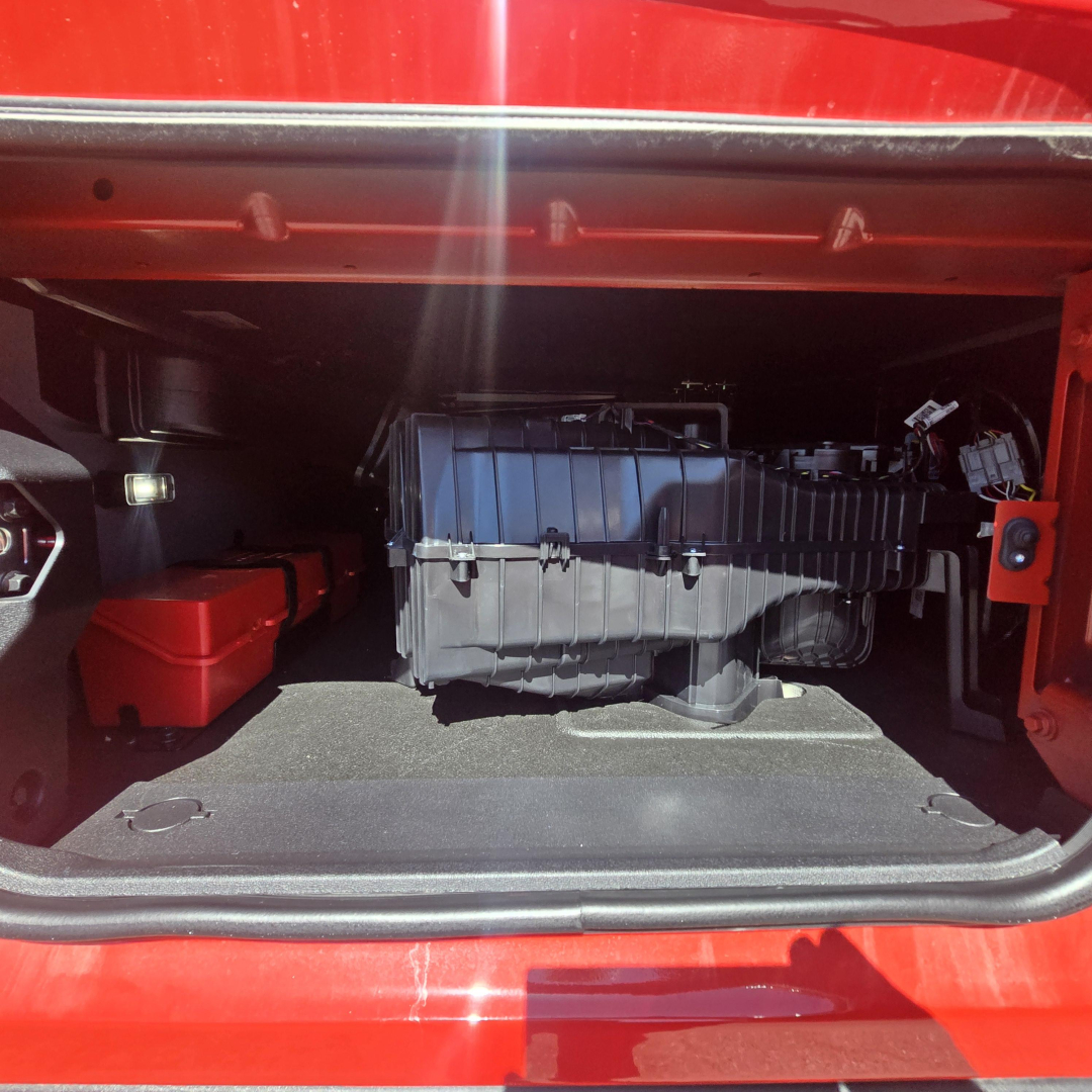Truck interior under cab showing electrical/air filter housing with black plastic box and red toolbox visible on left.