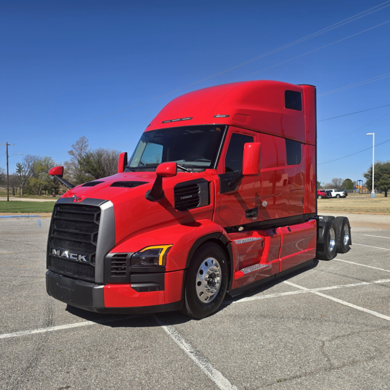 2026 Mack PR64T76H tractor-trailer cab in red, front-left view, with sleeper, chrome grille, large mirrors and dual rear axles.