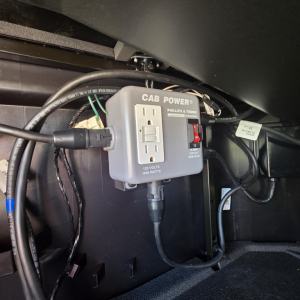 Cab Power electrical outlet device mounted under dashboard with two-prong outlet and switch labeled CAB POWER PHILLIPS TEMRO, in-service wiring harnesses visible.