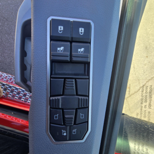 Mack truck interior door panel with multiple window/shutter and mirror controls, vertical layout of switches