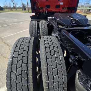 Dual rear axles with heavy-duty truck tires on a red Mack PR64T76H chassis, visible frame and suspension components.