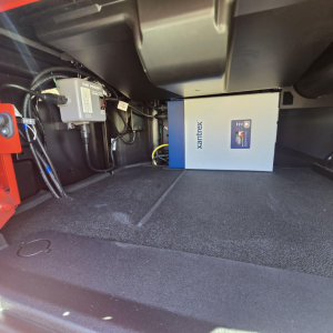Mack PR64T76H truck cab area showing Xantrex inverter box mounted in cargo bay with wiring and control module nearby.