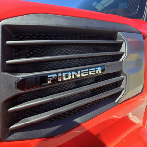 Pioneer grille of a red Mack truck showing glossy Pioneer badge and black vent slats.