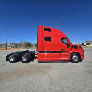 Semi truck tractor unit in red, side view showing sleeper cab and dual rear axles with fifth wheel, no trailer attached.