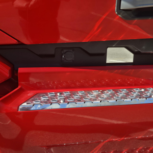 Truck step and door area of a red 2026 Mack PR64T76H showing metallic perforated step and black plastic trim.