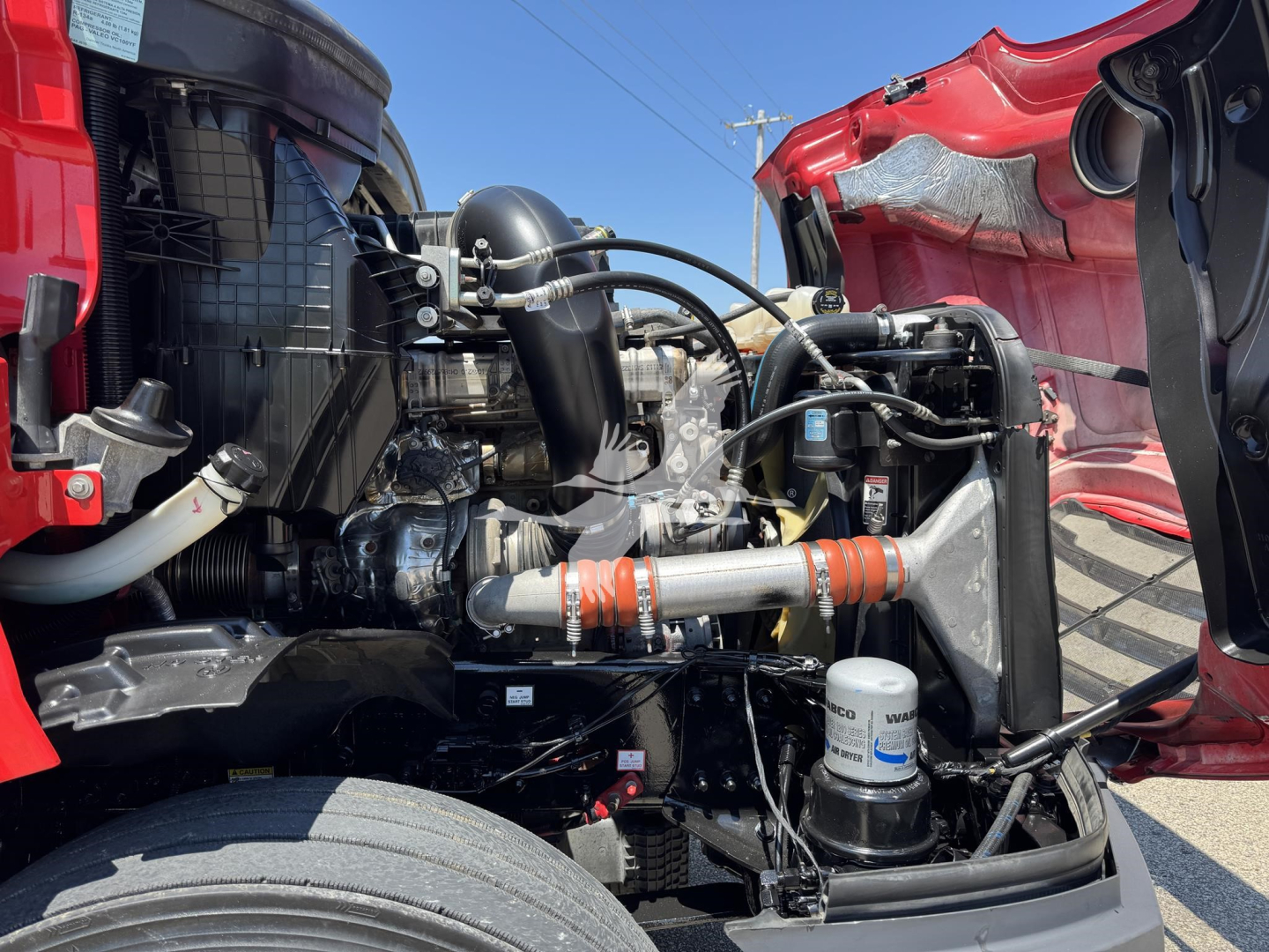 Truck engine bay of a Freightliner Cascadia 126 in-service showing coolant reservoir and various hoses, turbocharger, and filtration system.