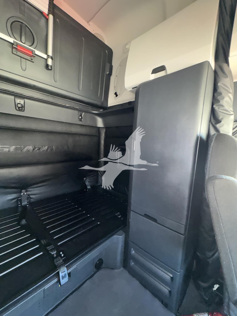 Interior of a Freightliner Cascadia sleeper cab showing storage compartments and a partition panel with visible text and components.