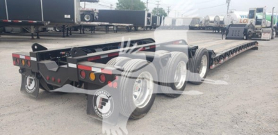 Screen image of a Fontaine 55Mx lowboy trailer showing dual rear axles and flatbed deck with spare tires and rear lights.