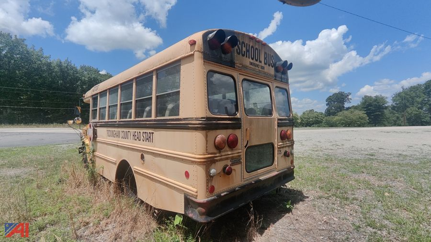 GMC/Thomas school bus rear and side view showing faded beige paint with 'SCHOOL BUS' and 'THOMAS BUILT SCHOOL BUS' lettering on the side. Windows along the body, rear bumper, and lights visible.
