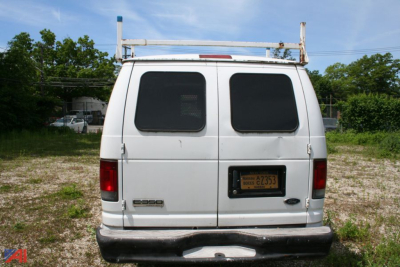 Ford E350 cargo van rear view showing dual rear doors, rear bumper, Rochester NY plate, ladder rack on top.