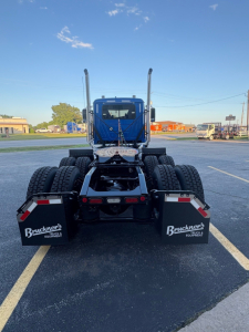 Front view of a 2026 Mack PI64T truck tractor in a parking lot, dual rear axles with large tires, blue cab, mudflaps labeled Bruckner’s Equipment, chassis and fifth wheel visible.