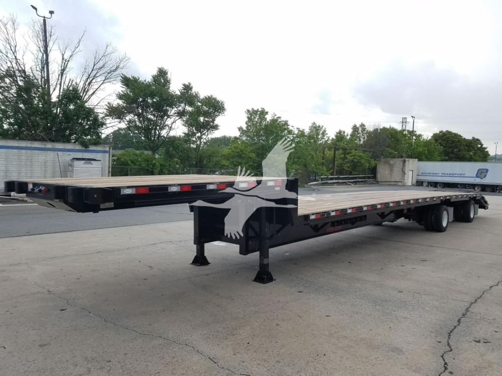 Beavertail dropdeck trailer in a parking lot showing landing gear and extended deck with logo outline near front