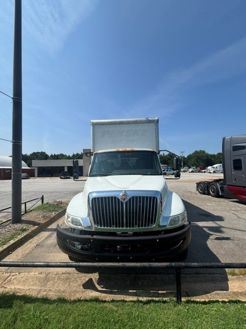 Front view of a white 2021 International MV607 box truck with a chrome grille and cargo box, parked in a lot.