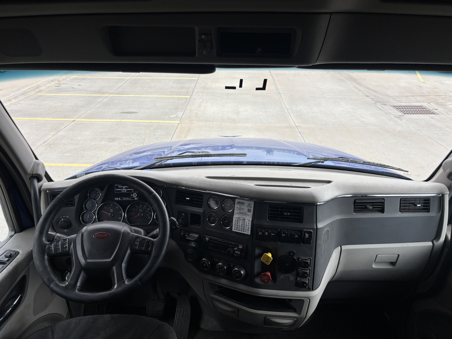 Truck cab interior dashboard of a 2019 Peterbilt 579 front view, steering wheel, gauge cluster, center console with switches and vents.