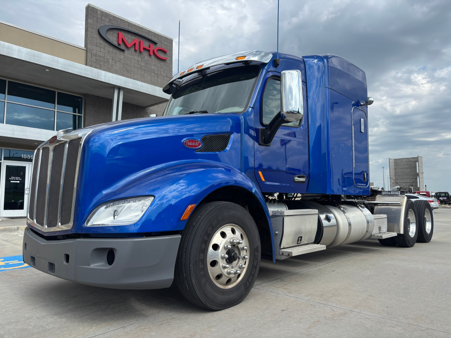 Blue 2019 Peterbilt 579 conventional sleeper truck parked in lot, front view, showing chrome grille, dual fuel tanks, and side steps.