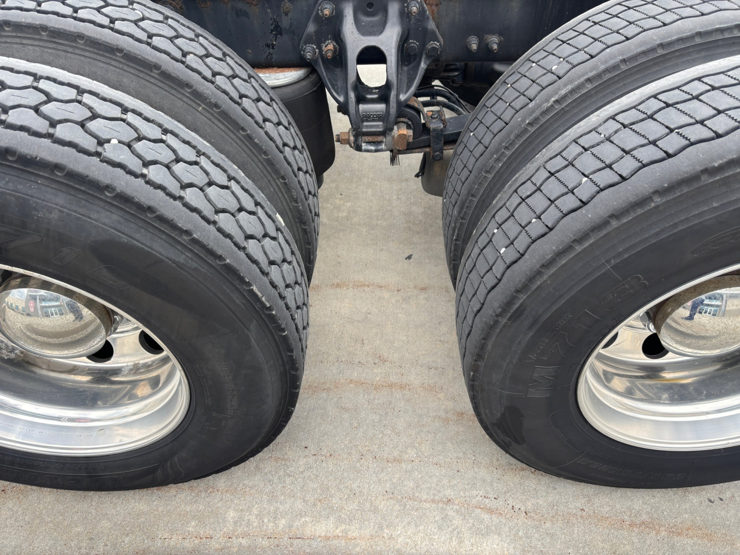 Peterbilt 579 truck dual rear wheels with chrome rims and undercarriage components visible, part of drivetrain and suspension in center.