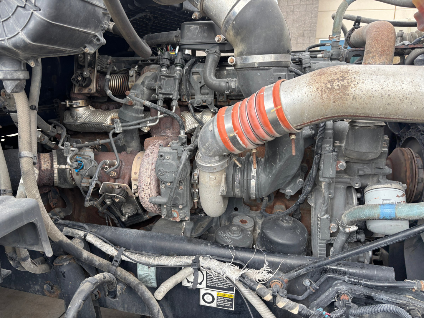 Peterbilt 579 engine bay showing turbocharger and intake piping with hoses and wiring visible.