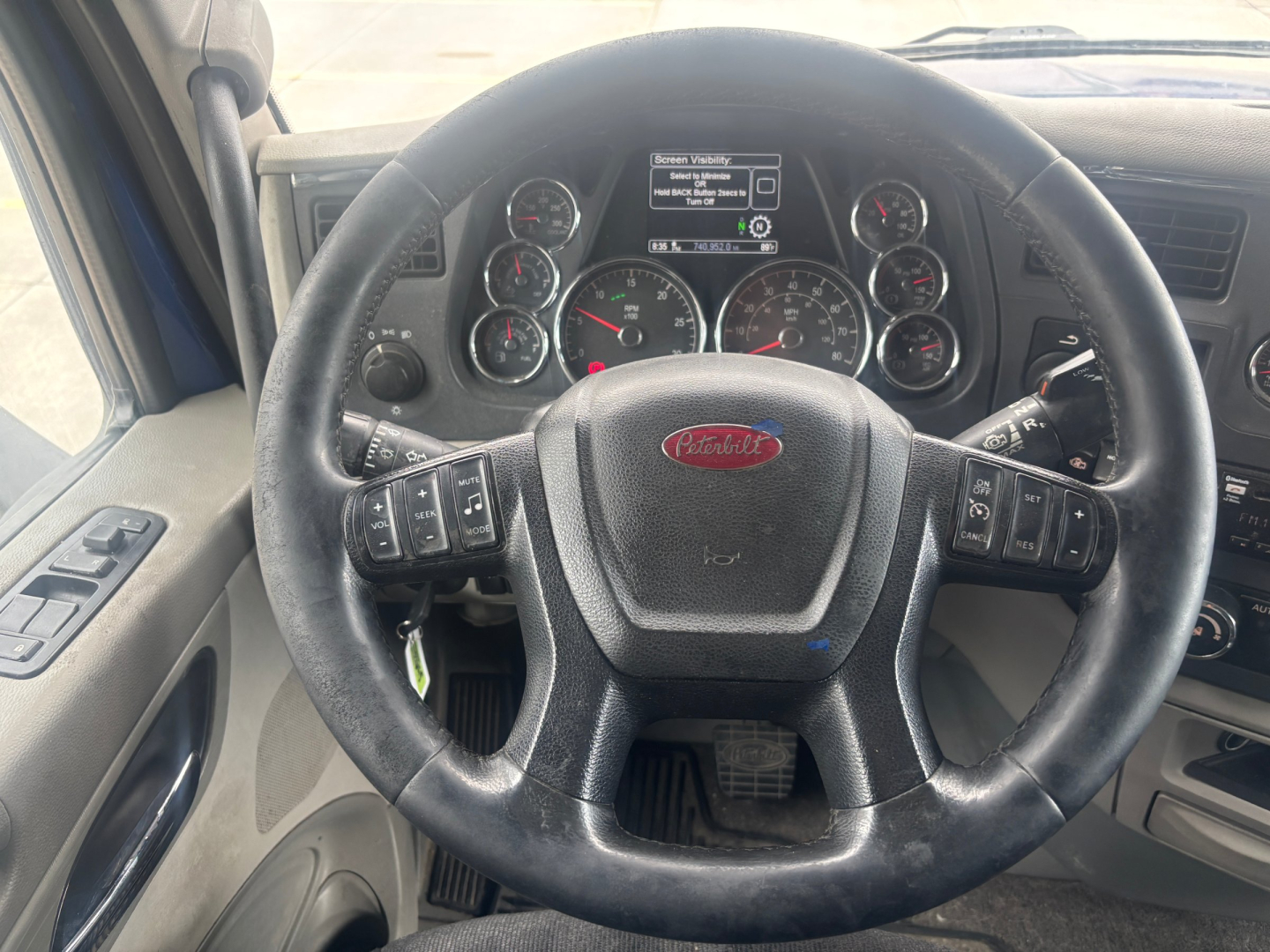 Peterbilt 579 truck interior steering wheel and dashboard with multiple gauges and controls.