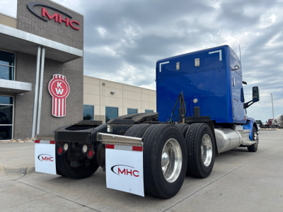 Peterbilt 579 tractor showing rear wheels and blue sleeper cab, with MHC building in background.