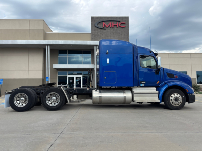 Peterbilt 579 conventional sleeper tractor in blue side profile showing cab, fuel tanks, and dual rear axles.
