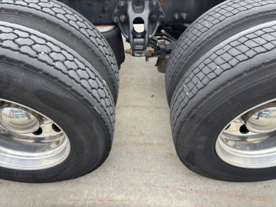 Peterbilt 579 truck dual rear wheels with chrome rims and undercarriage components visible, part of drivetrain and suspension in center.