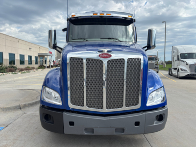 Peterbilt 579 front view showing blue cab, chrome grille, large side mirrors, daytime running lights, and black bumper.
