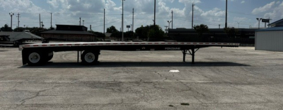 Trailer in a lot showing a Fontaine 48' combo flatbed trailer with black deck and dual rear axles, side rails, and gooseneck support visible.