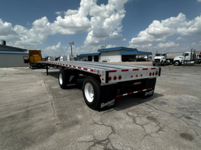 Flatbed trailer showing rear with multiple taillights and reflective rear bumper, Fontaine logo on mudflaps, aluminum deck with side rails.