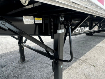 Trailer landing gear and frame with Fontaine branding on a 48' combo flatbed trailer showing support legs, hydraulic lines, and safety decals.