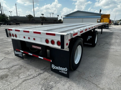 Flatbed trailer showing silver aluminum deck with red/white reflective tape, dual rear axles, taillights, and black fenders with Bracken’s mudflaps; Fontaine logo on rear bumper in verification area.