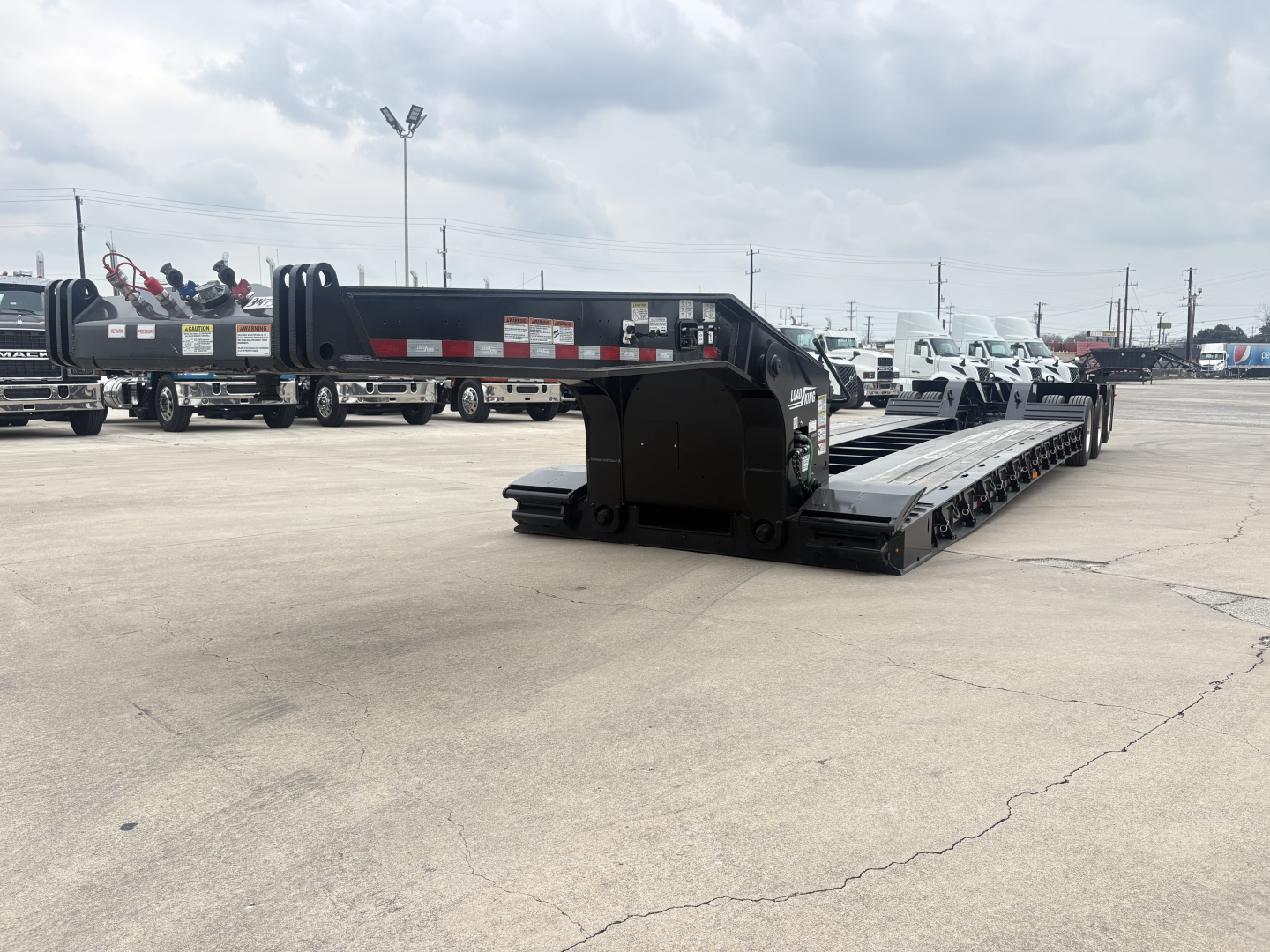 Load King lowboy trailer with 8'-6" deck height, 20" wheels visible, long black trailer with deck, front gooseneck area and ramp sections, parked in lot.