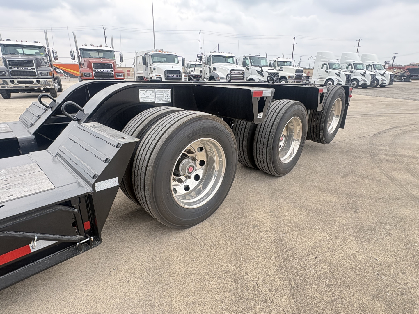 Trailer chassis and dual-axle configuration of a Load King lowboy trailer with three axles visible, large tires, and reflective markers.
