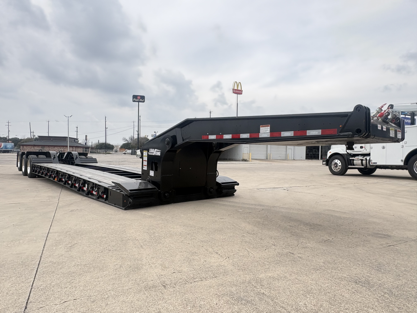 Load King lowboy trailer in transport position showing main deck and gooseneck with reflective tape.