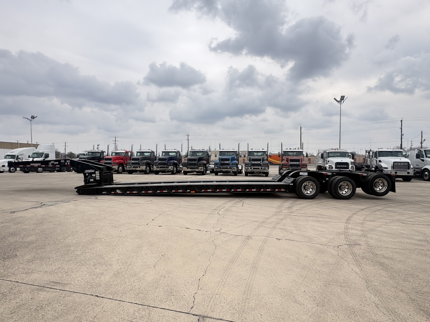 Load King trailer lowboy configuration showing side profile with long steel deck and multiple axles.