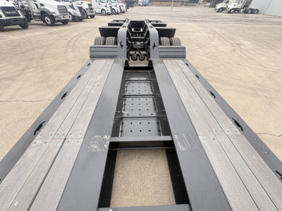 Lowboy trailer deck showing heavy-duty steel frame and twin-axle setup with Fifth-wheel hitch and tie-down rails, 2025 Load King model 503/605-8'-6"-20".