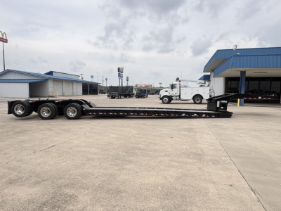 Lowboy trailer showing multi-axle rear bogies and long flatbed with a gooseneck, Load King branding likely present.