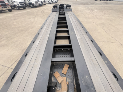 Load King trailer bed showing long steel deck with multiple tie-down slots and wooden blocks on the bed.
