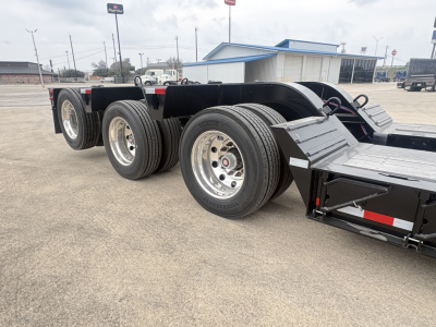 Lowboy trailer showing tandem axles and chrome wheels with black frame and deck, 3rd axle visible, Load King branding implied by listing.