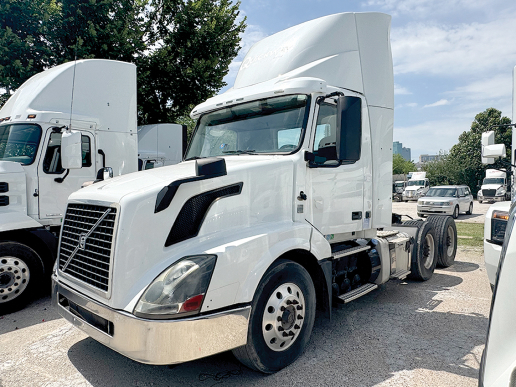 Truck cab-forward view of a 2015 Volvo VNL 300 daycab showing side and front with white paint and chrome bumper.