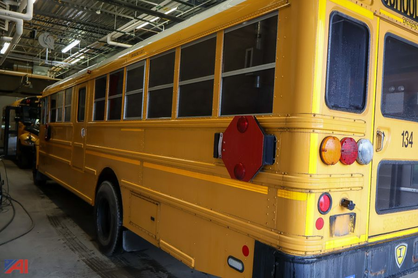 School bus CE Series 2011 IC Corporation rear-right view showing yellow body, windows, red safety beacon near tail, and rear lights.