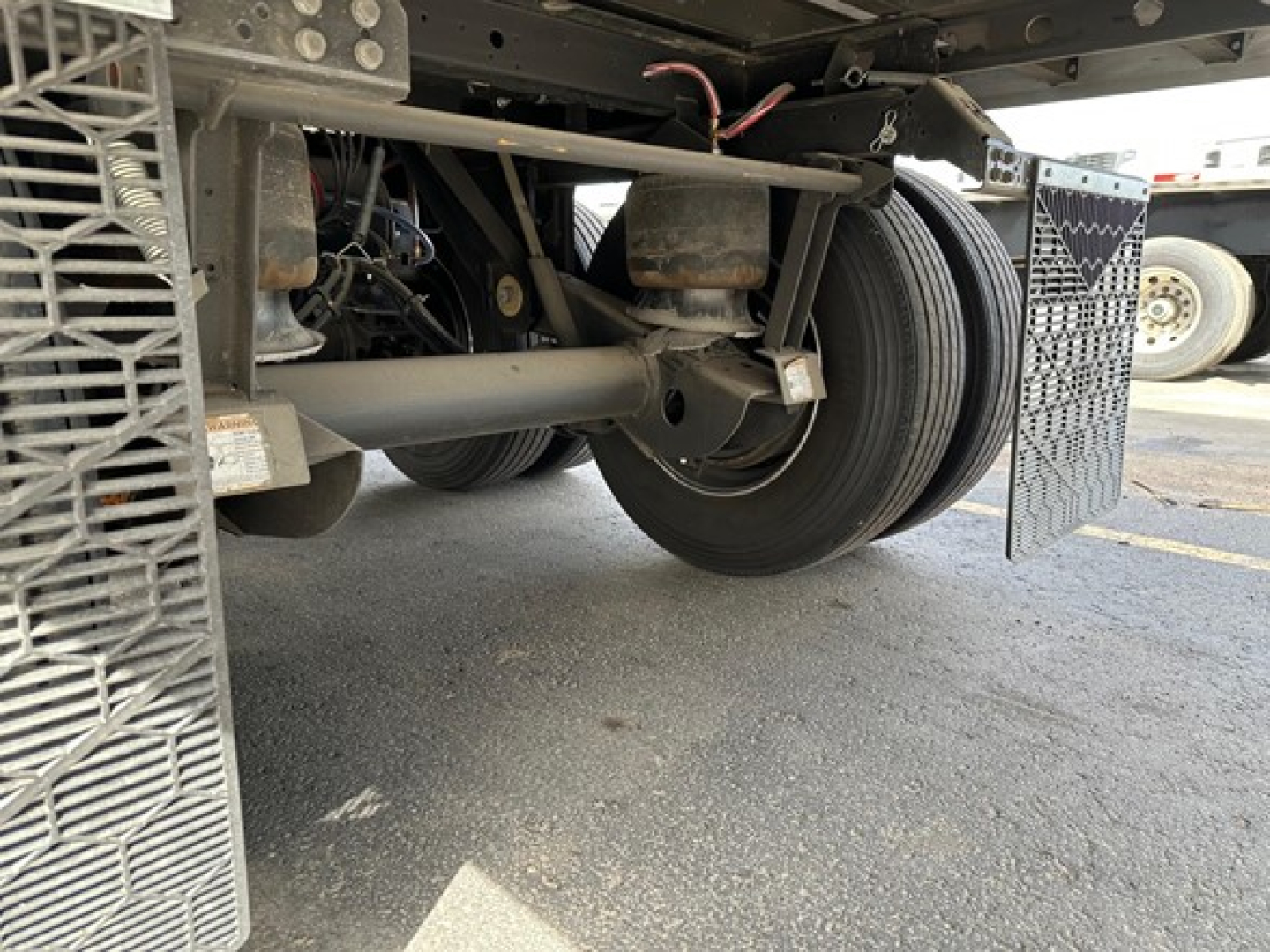 Trailer undercarriage showing axle, suspension, and dual wheels with a metal ramp/step visible on the side of a 2026 Utility 3000R reefer trailer.
