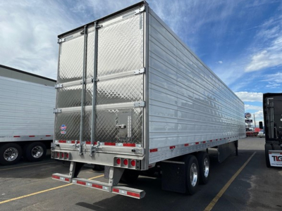 Trailer rear view showing aluminum box trailer with diamond plate doors and dual rear wheels.