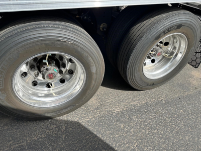 Trailer dual rear tires and chrome rims with metallic wheel hubs, undercarriage visible, side of reefer trailer in view.